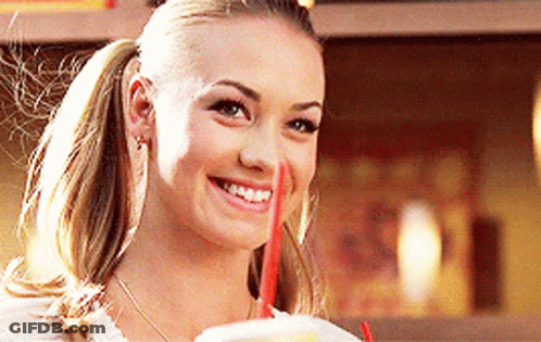 Woman In Ponytail Smiling And Drinking From Cup With Red Straw GIF