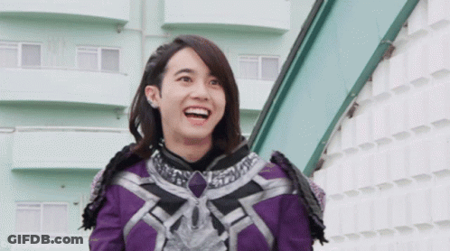 Woman In Purple And Black Outfit Smiling In Front Of Building GIF