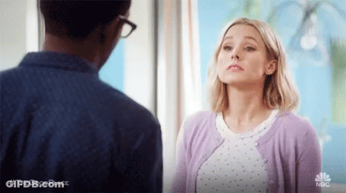 Woman In Purple Cardigan Looking At Man In Blue Shirt GIF