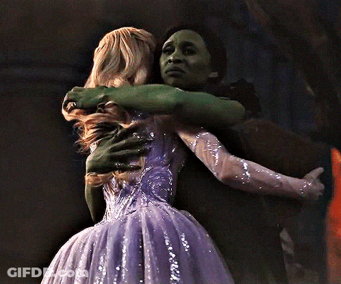 Woman In Purple Dress Hugging Woman In Green Dress GIF