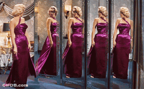 Woman In Purple Dress Looking In Mirror GIF
