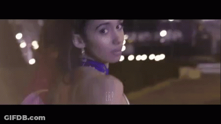 Woman In Purple Dress Standing In Front Of Blurry Lights GIF