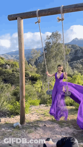 Woman In Purple Dress Swinging On Swing GIF