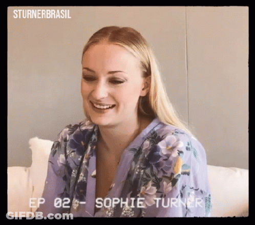 Woman In Purple Floral Shirt Smiling On Couch GIF