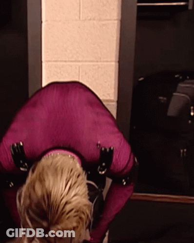 Woman In Purple Outfit Kneeling Before Brick Wall GIF
