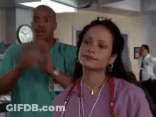 Woman In Purple Scrubs Next To Man In Green Scrubs GIF