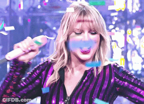 Woman In Purple Sequined Top Blowing Confetti With Microphone GIF