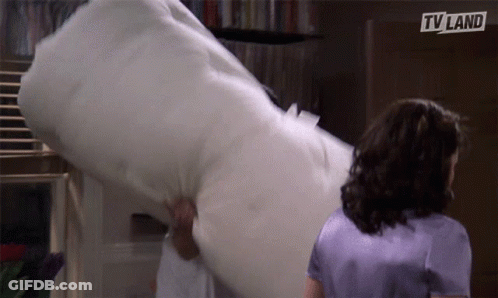 Woman In Purple Shirt Next To Man Holding TV Land Pillow GIF