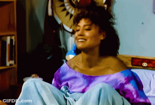 Woman In Purple Shirt Sitting On Bed GIF