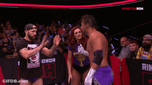 Woman In Purple Shirt With Cross Next To Man In Purple Shorts GIF