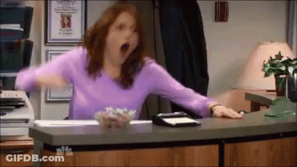 Woman In Purple Shirt Yawning At Desk GIF