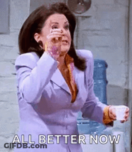 Woman In Purple Suit Holding Coffee Wiping Nose GIF