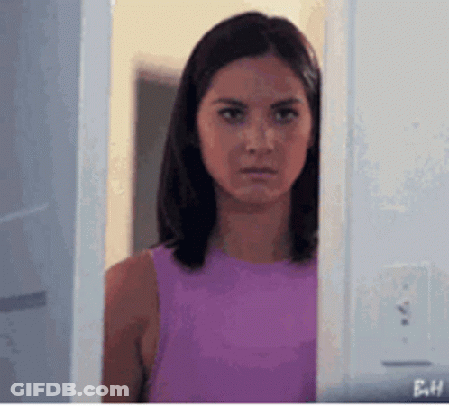 Woman In Purple Tank Top Peeking From Behind Door GIF