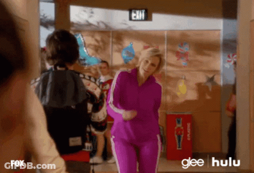 Woman In Purple Tracksuit Dancing In Hallway With Exit Sign GIF