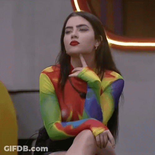 Woman In Rainbow Shirt Sitting With Hand On Chin GIF