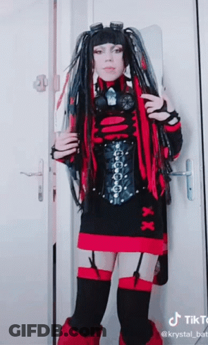 Woman In Red And Black Costume In Front Of Door With TikTok Logo GIF