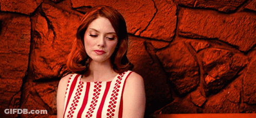 Woman In Red And White Striped Dress Sitting By Red Stone Wall GIF