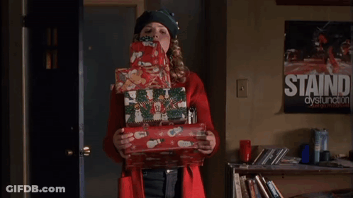Woman In Red Coat Holding Christmas Presents In Front Of Staind Dysfunction Poster GIF