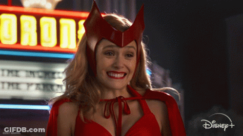 Woman In Red Costume Smiling In Front Of Orion Sign GIF