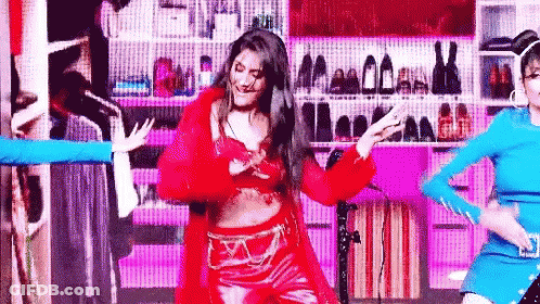 Woman In Red Dancing On Stage Before Wall Of Shoes GIF
