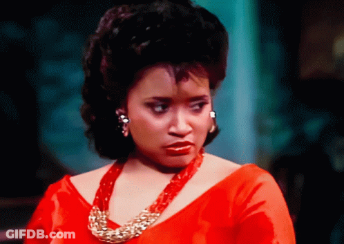 Woman In Red Dress And Gold Necklace Looking At Camera GIF