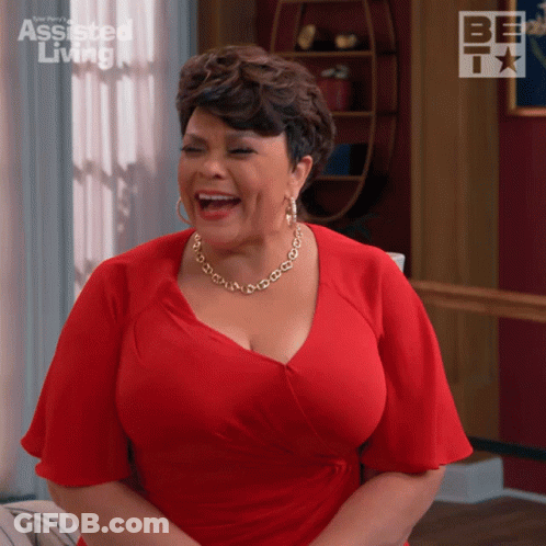 Woman In Red Dress Laughing In Front Of Assisted Living Sign GIF