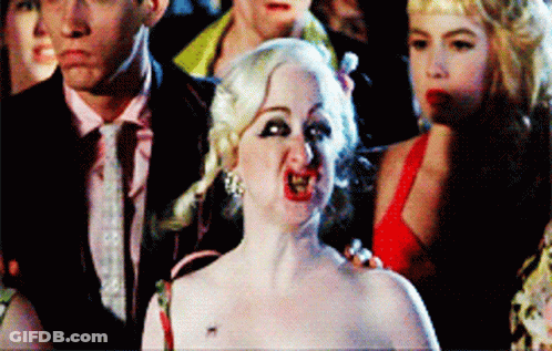 Woman In Red Dress Making Funny Face In Front Of Crowd GIF