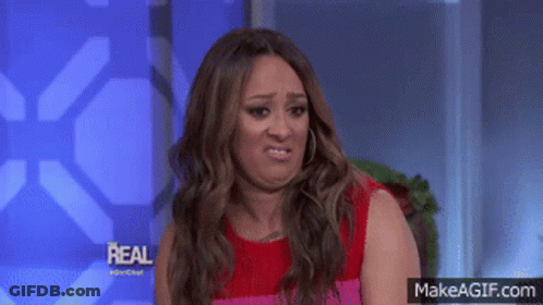 Woman In Red Dress Making Funny Face In Front Of Real Sign GIF