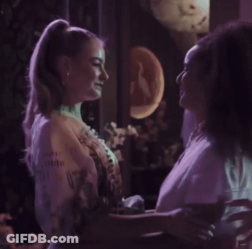 Woman In Red Dress Next To Woman In White Coat GIF