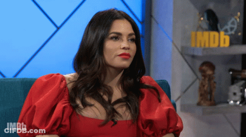 Woman In Red Dress Sitting In Front Of IMDb Sign GIF