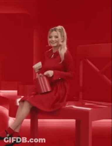 Woman In Red Dress Sitting On Red Bench Holding Red Purse GIF