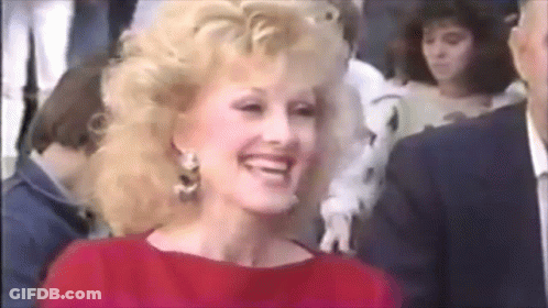 Woman In Red Dress Smiling In Crowd GIF