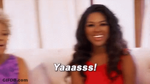 Woman In Red Dress Smiling On Couch GIF