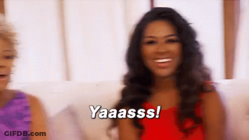 Woman In Red Dress Smiling While Another Says Yaaass GIF