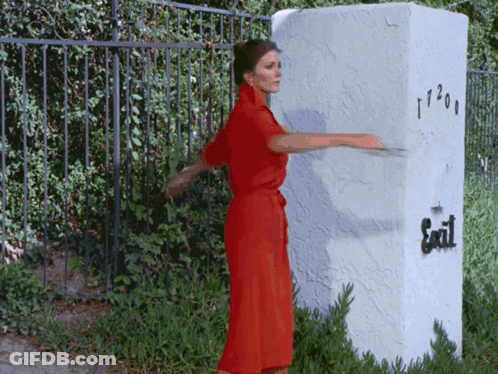 Woman In Red Dress Standing By Exit Sign GIF