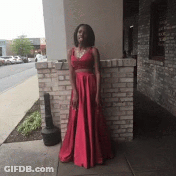 Woman In Red Dress Standing In Front Of Brick Building GIF