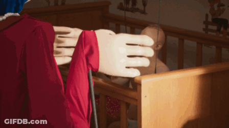 Woman In Red Dress Standing In Room With Dresser And Crib GIF