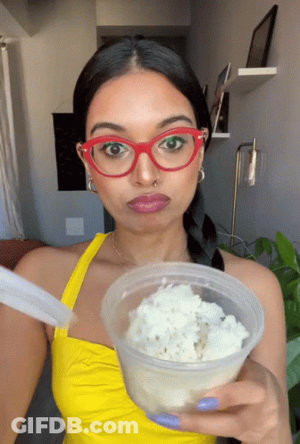 Woman In Red Glasses And Yellow Top Holding Food Container GIF