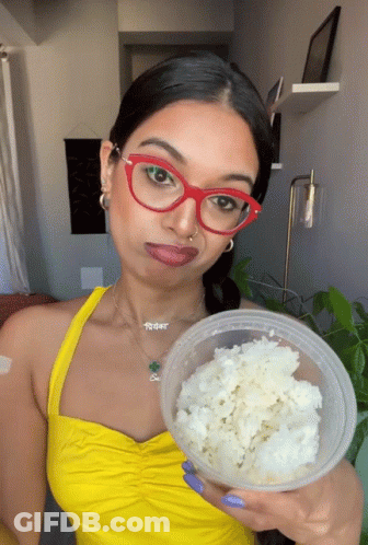 Woman In Red Glasses And Yellow Top Holding Rice Container GIF