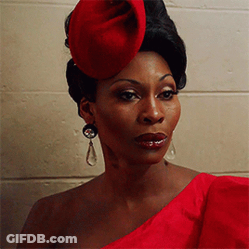 Woman In Red Hat And Earrings In Front Of Brick Wall GIF