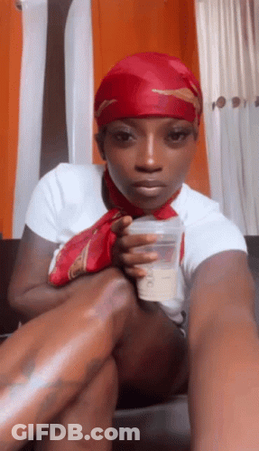 Woman In Red Head Scarf Sitting On Couch Holding Cup GIF