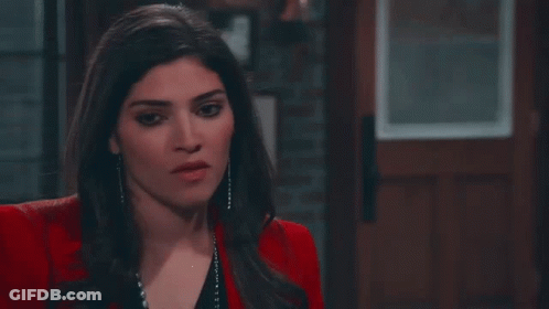 Woman In Red Jacket And Black Top Standing Before Door GIF