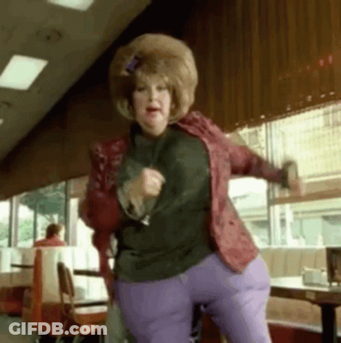 Woman In Red Jacket And Purple Pants Dancing In Restaurant GIF