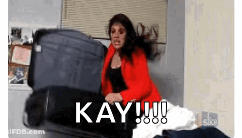 Woman In Red Jacket Holding Suitcase Saying Kay GIF