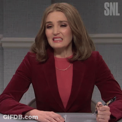 Woman In Red Jacket Sitting At Desk With Pen Saying Oof GIF