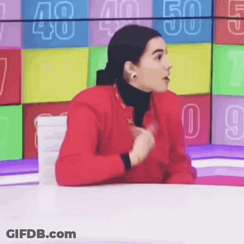 Woman In Red Jacket Sitting At Table With Numbers GIF