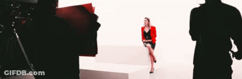 Woman In Red Jacket Sitting On White Couch GIF