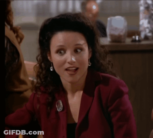Woman In Red Jacket Surprised At Table GIF