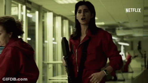 Woman In Red Jumpsuit Holding Gun GIF