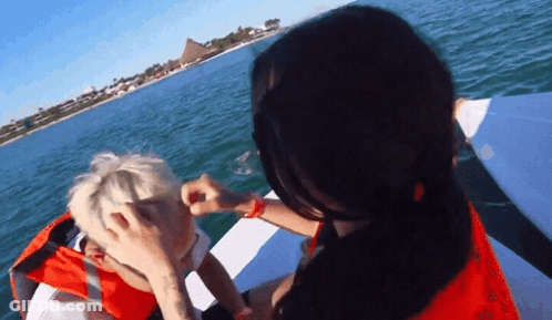 Woman In Red Life Jacket Putting Makeup On Boy GIF